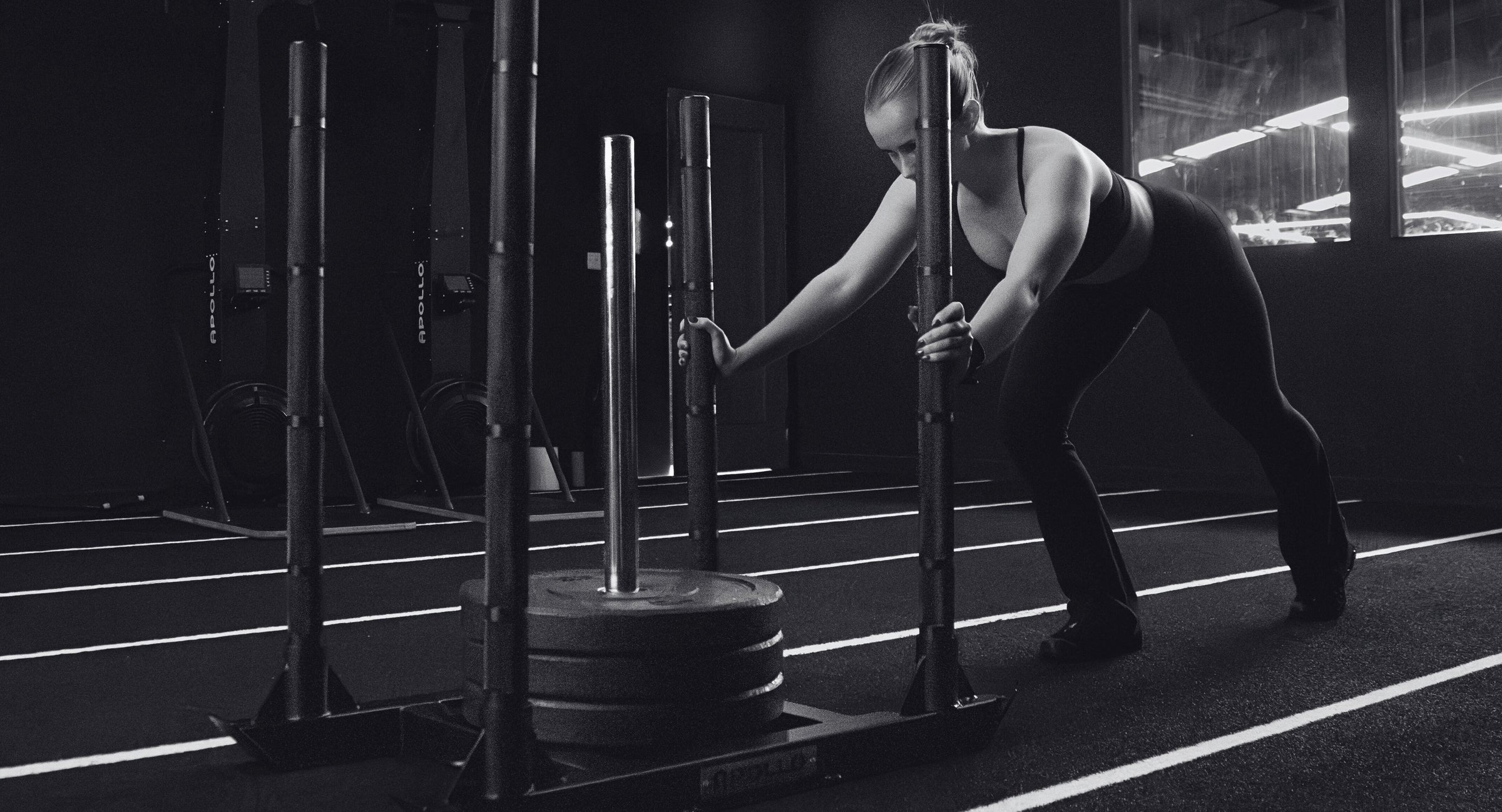Person performing a weightlifting exercise with a barbell in a gym setting.