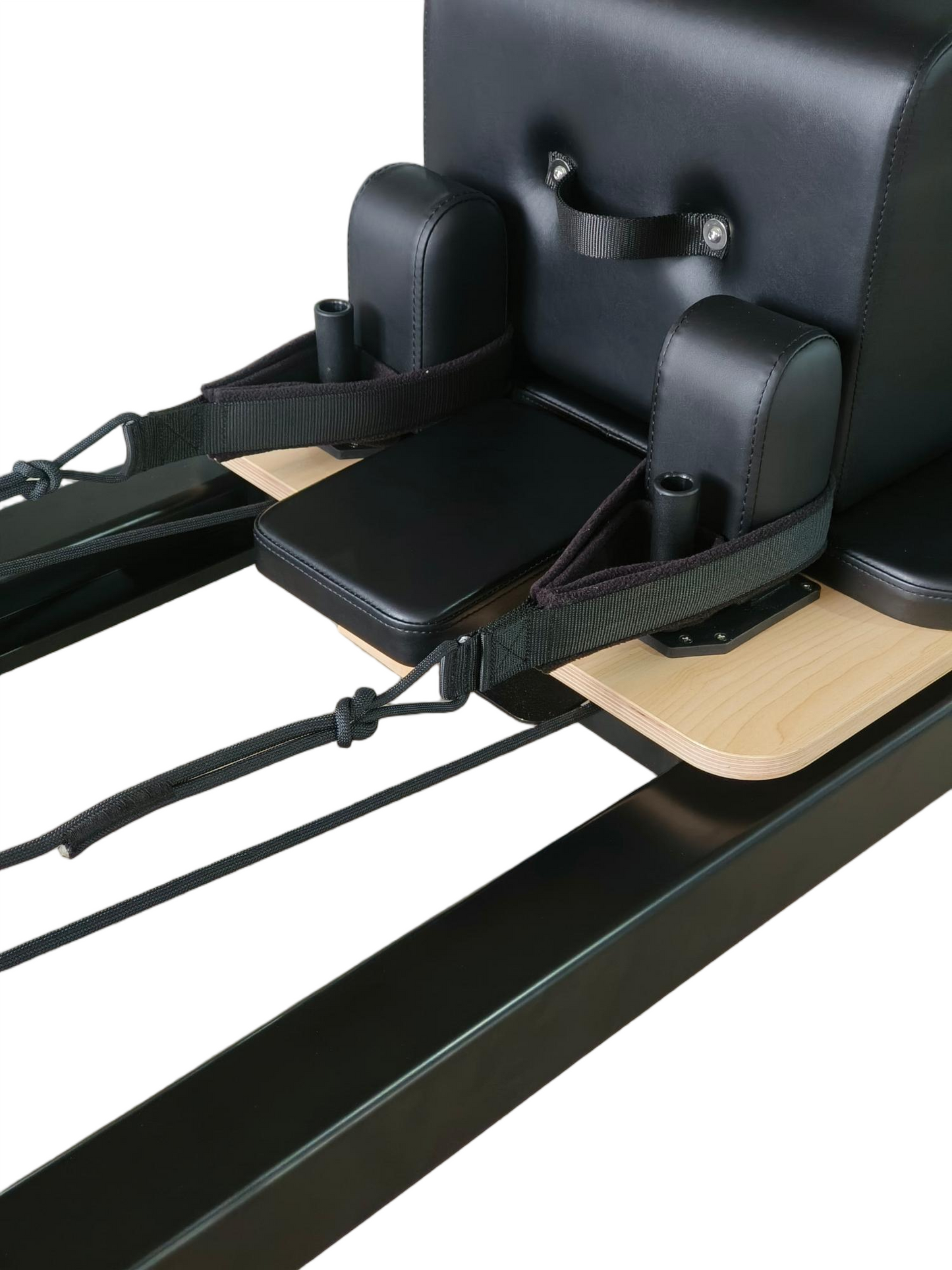 Pilates reformer machine with black cushioned seat and wooden platform on a white background